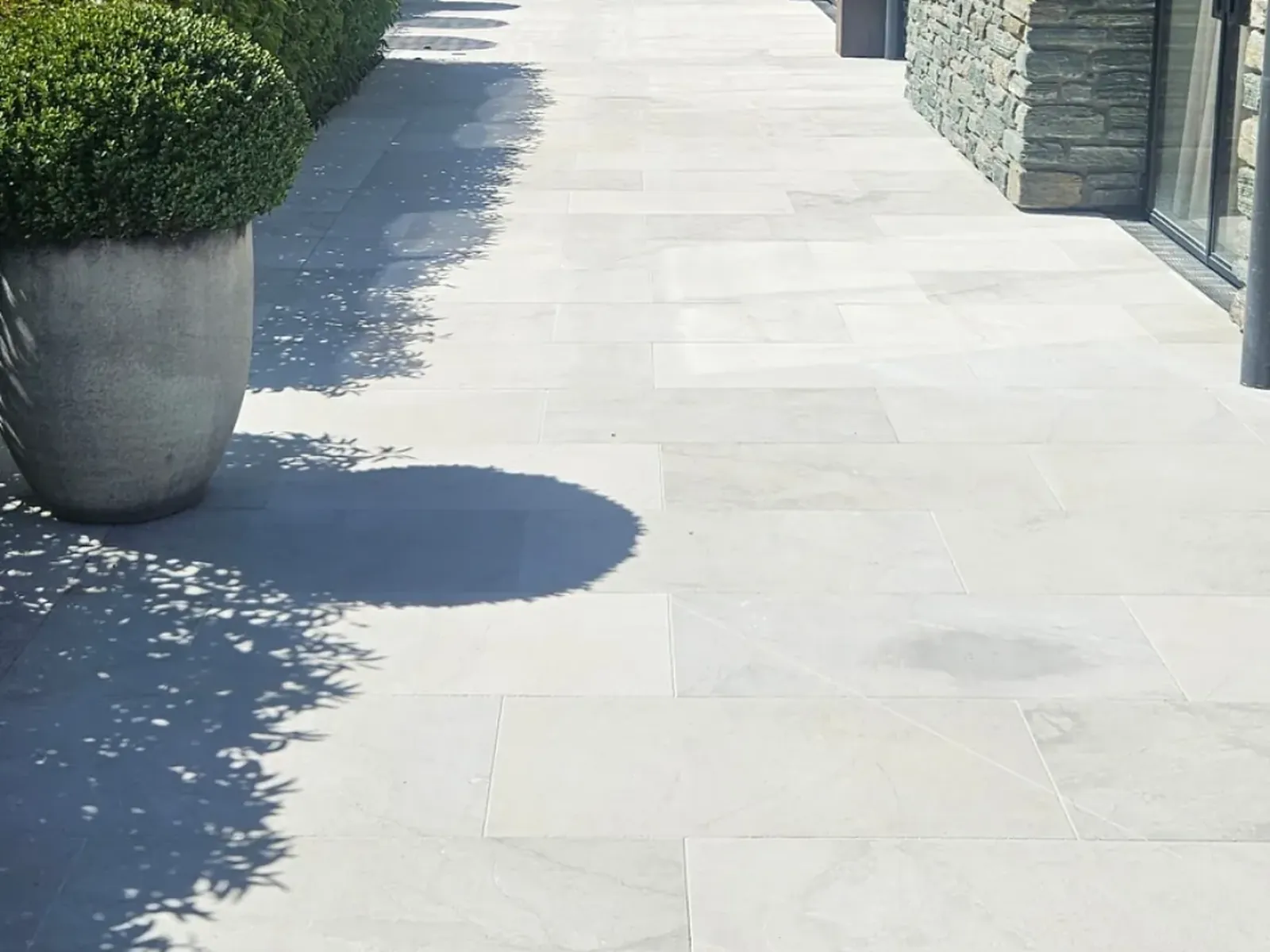 Pale limestone walkway alongside the schist wall after cleaning, Wanaka